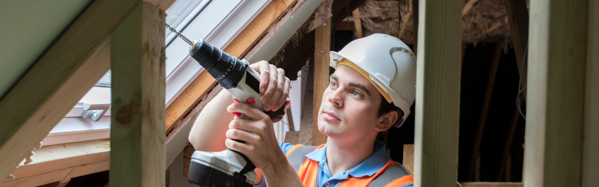 carpenter uses drill to install replacement window